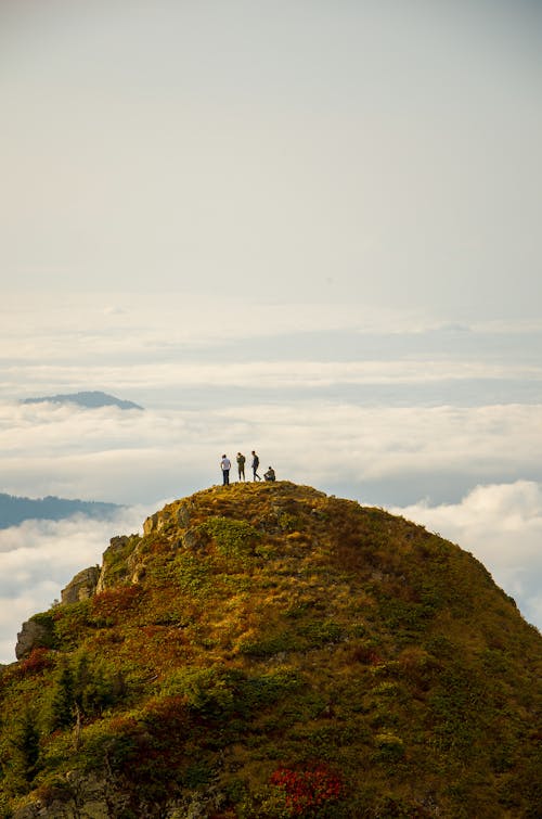 Orang Berdiri Di Puncak Gunung Rumput Dekat Awan Pada Siang Hari