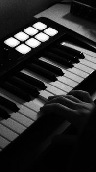 Black and white image of a hand playing a keyboard piano, showing musical creativity.