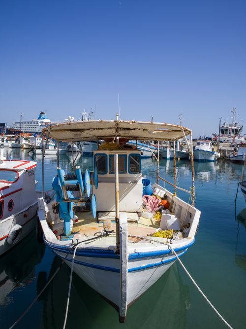 Free Rustic fishing boat docked at a serene Mediterranean harbor on a sunny day. Stock Photo
