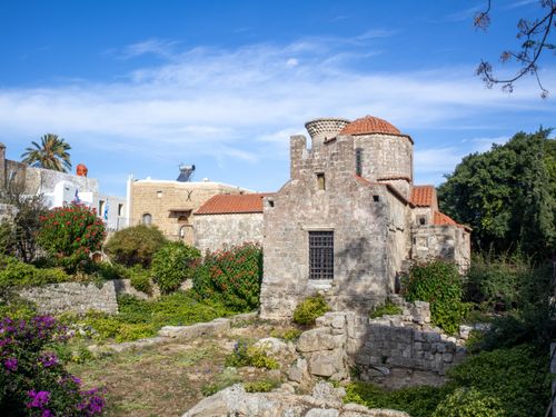 Free Beautiful historic stone building with lush garden under a clear blue sky, capturing Mediterranean architecture. Stock Photo