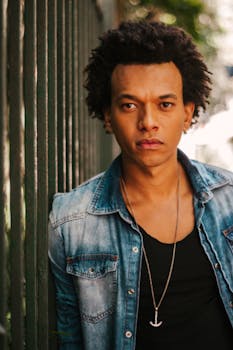 在圣保罗，一位卷发的时尚年轻人正在户外栅栏旁摆姿势