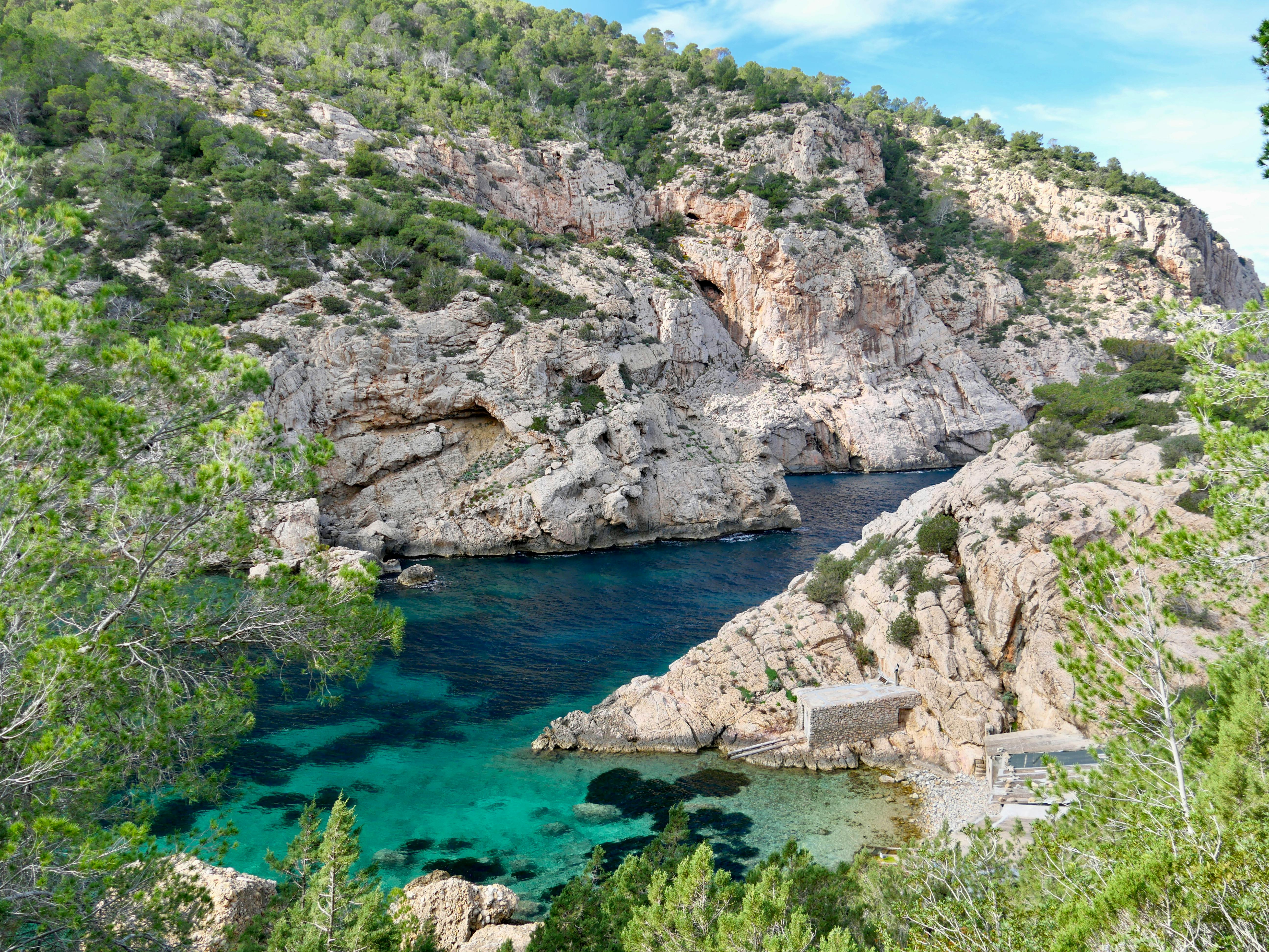 Blick in wildromantische Bucht mit Bootsschuppen auf Ibiza