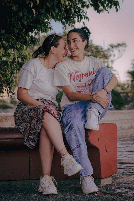 Two young women sitting together, laughing and enjoying a joyful moment outdoors on a bench.