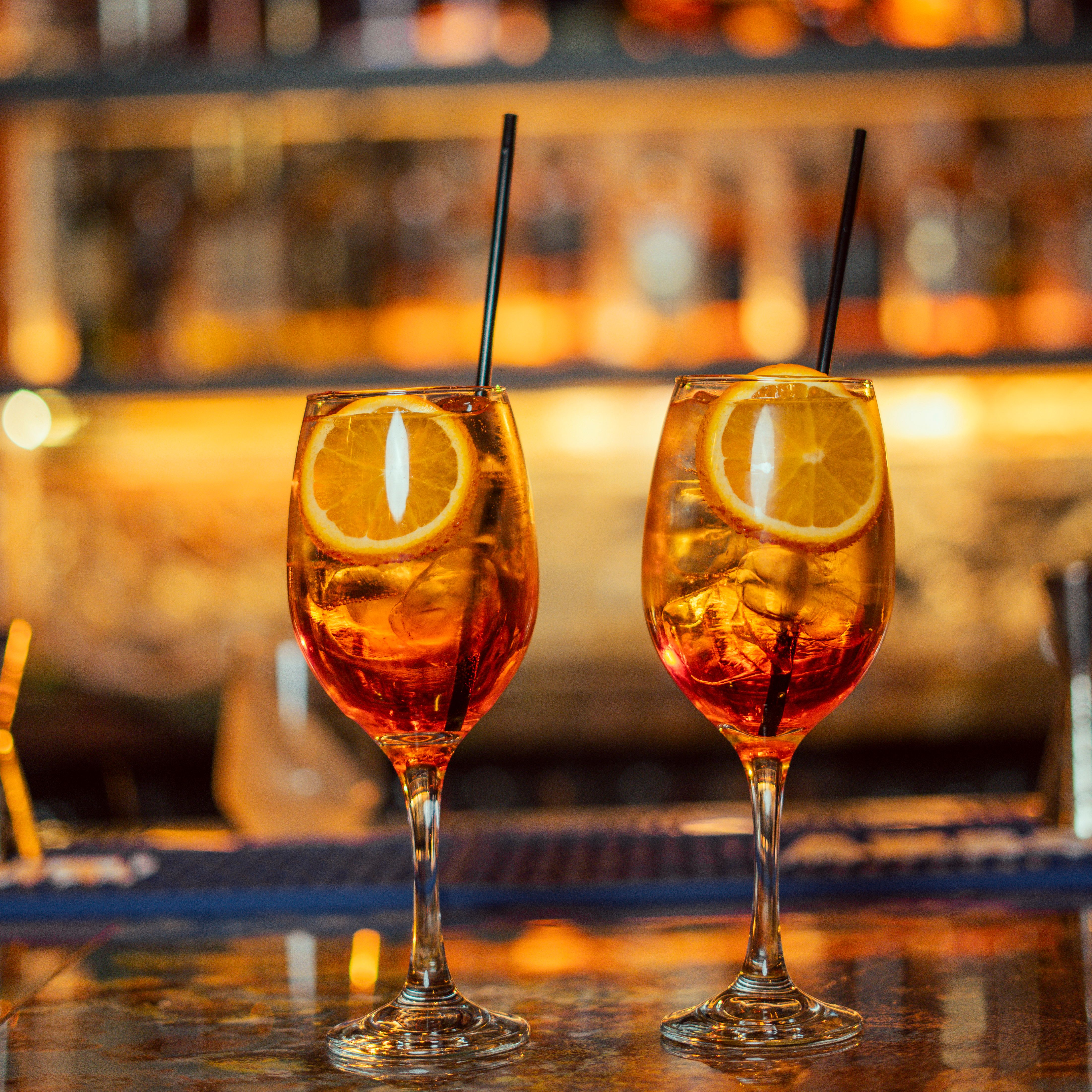 Gratis To Aperol Spritz-cocktails med appelsinskiver, perfekt til en feststemning i hyggelige bar-miljøer. Lagerfoto