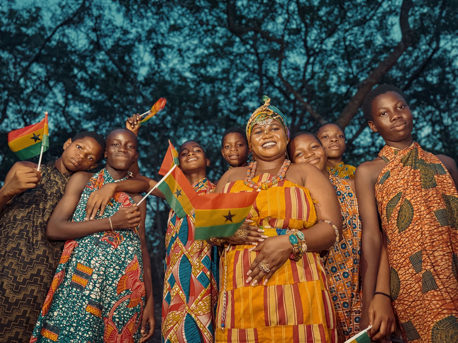 Ghanaians in traditional attire celebrate with national flags, showcasing vibrant kente cloth.