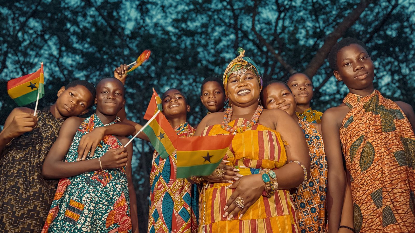 Ghanaians in traditional attire celebrate with national flags, showcasing vibrant kente cloth.