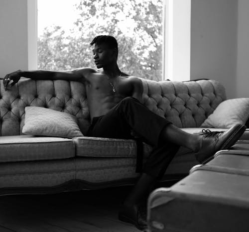 Monochrome Photo Of Man Sitting On Sofa