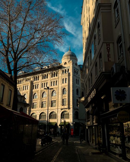 Free A vibrant city street with historical architecture and shops under a clear blue sky. Stock Photo