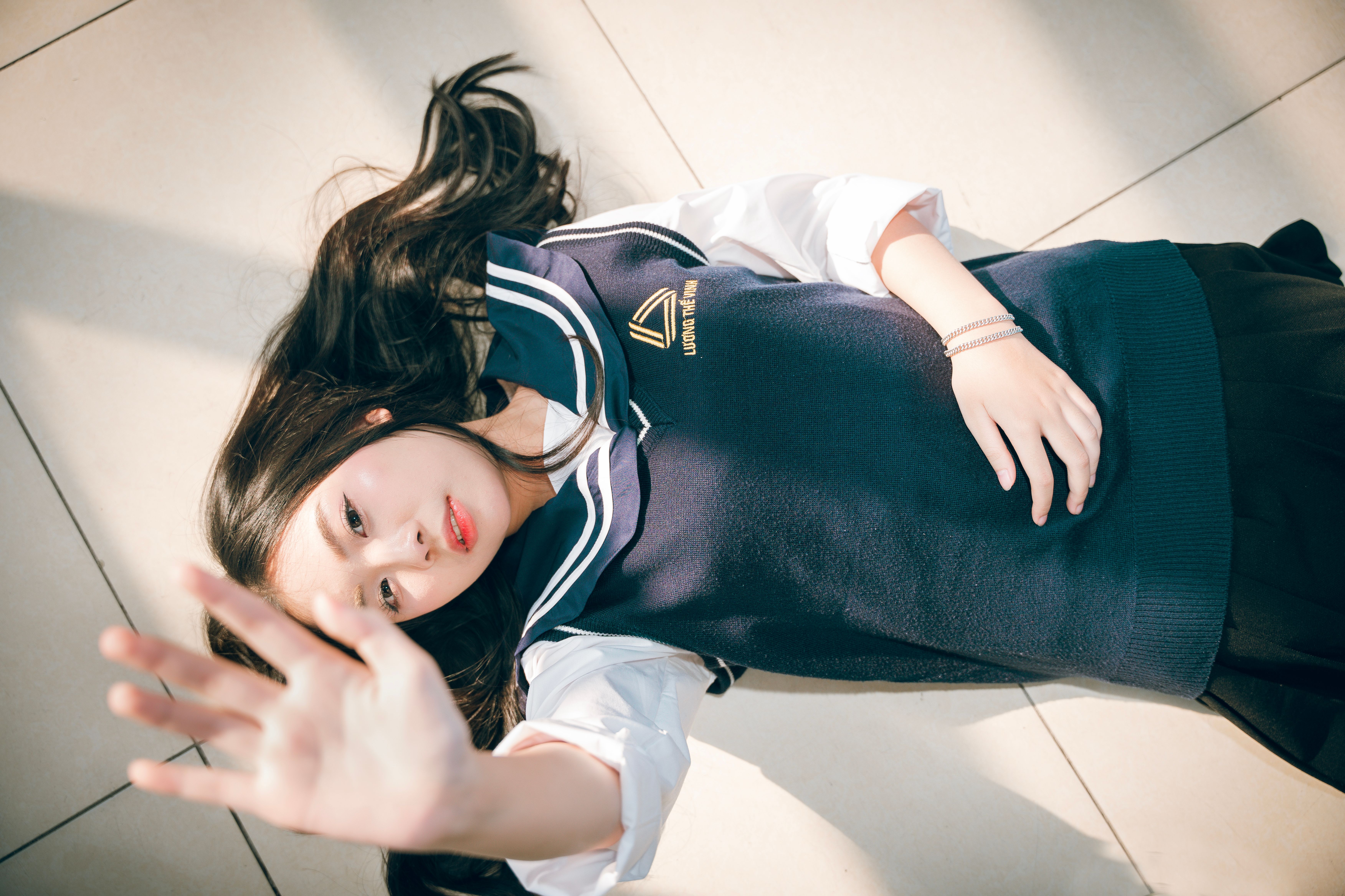 Young Woman in School Uniform Lying Outdoors · Free Stock Photo