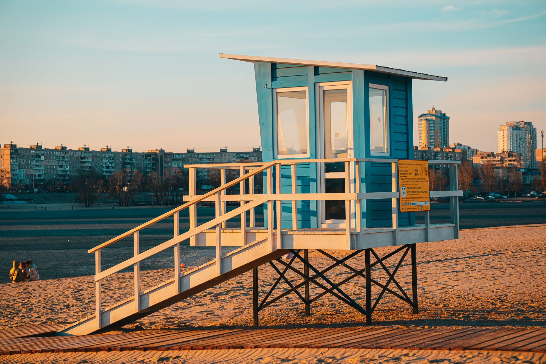A serene sunset casts warm tones on a blue lifeguard stand at Kyiv beach.