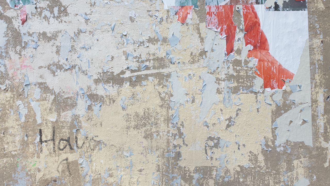 close up of a weathered wall with peeling posters and exposed textures