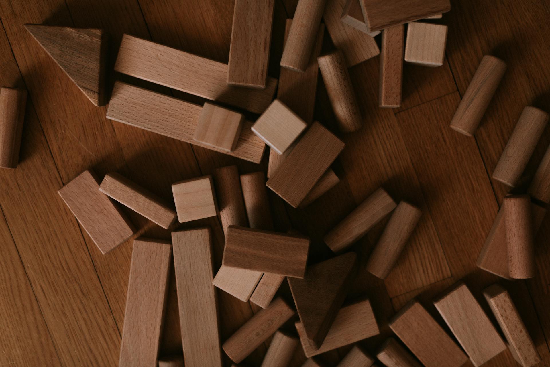 Top view of assorted wooden blocks spread on a wooden floor, creating a playful scene.