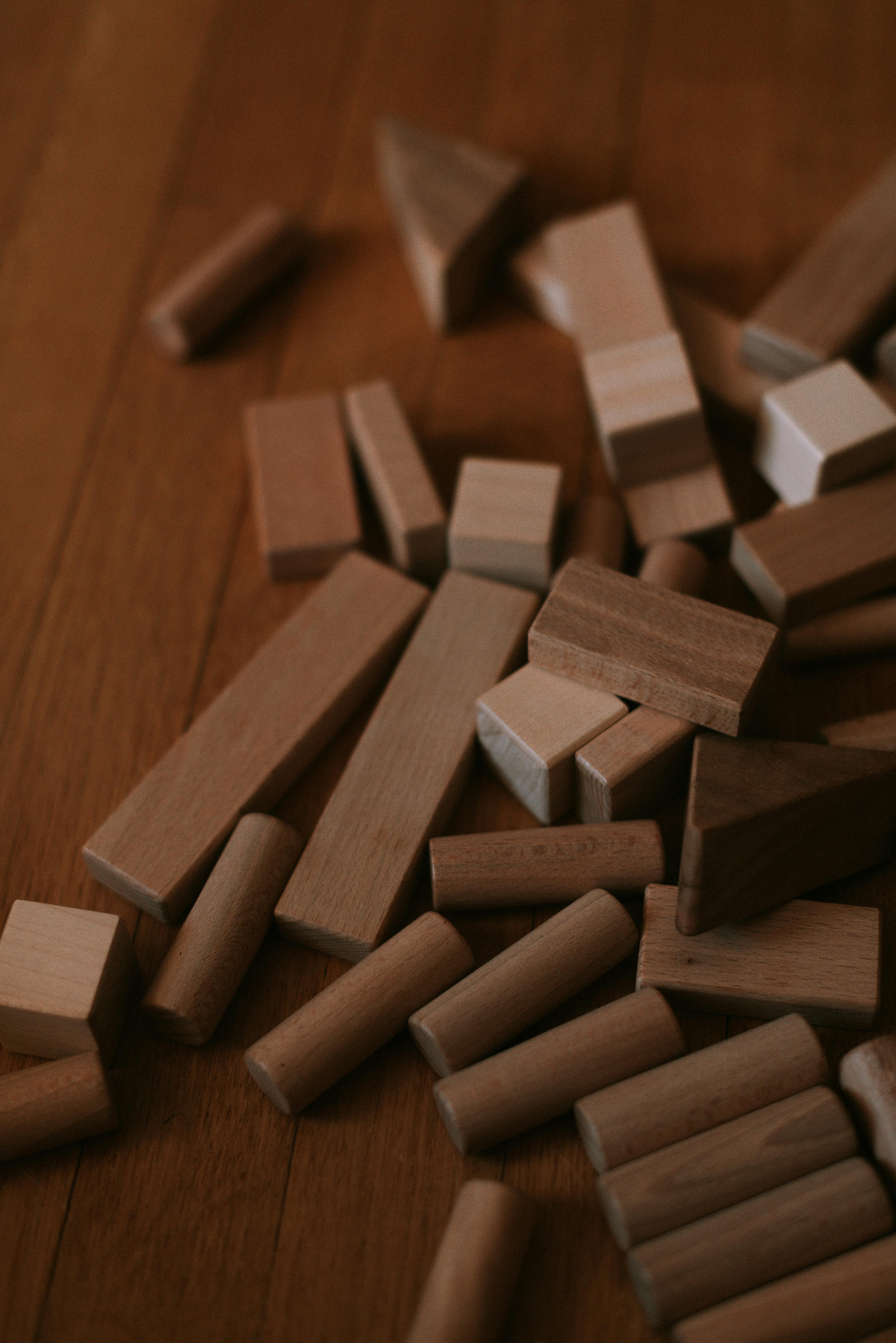 Wooden building blocks scattered on a hardwood floor, offering a warm, minimalist feel.