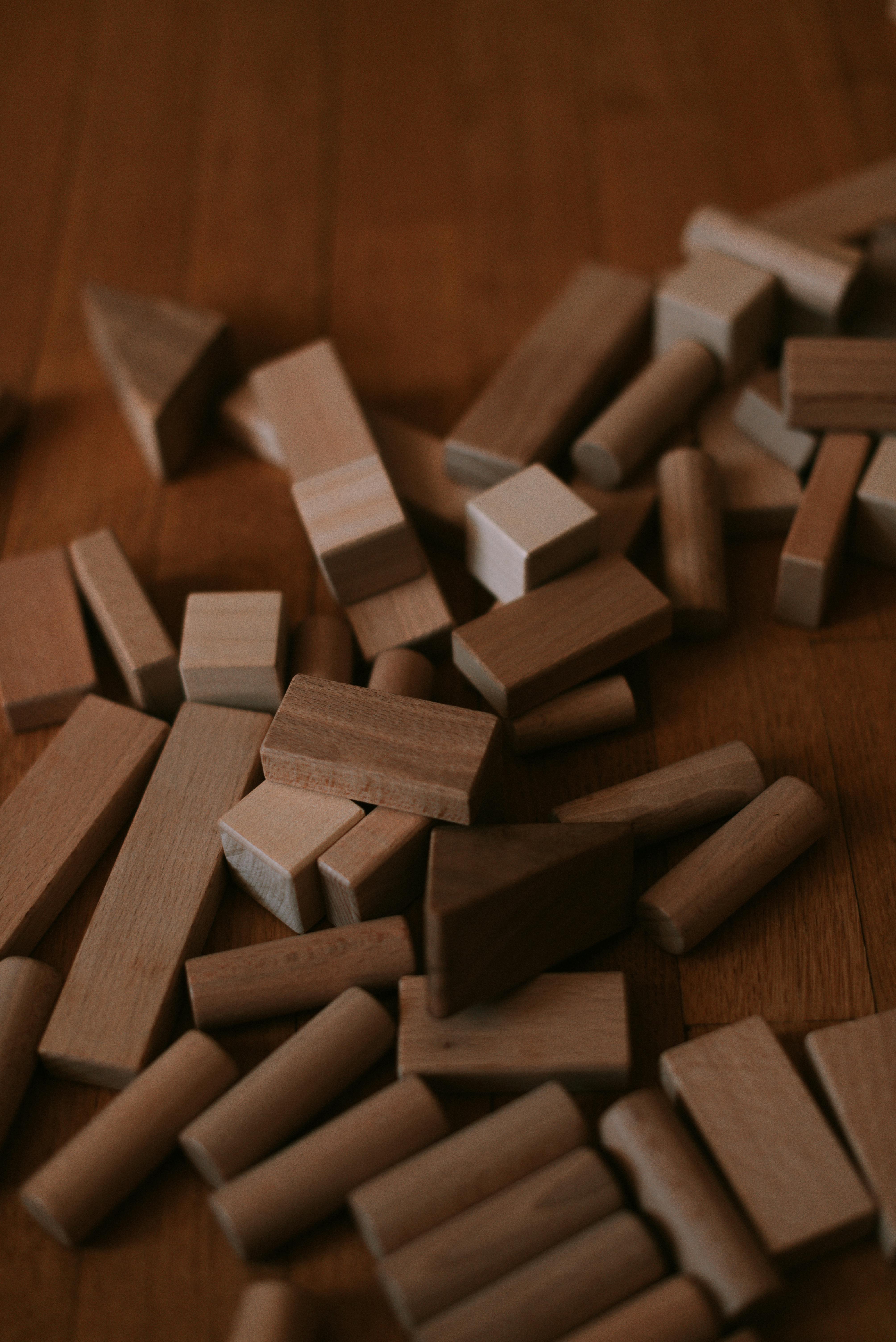 A scattered collection of natural wooden building blocks on a wooden surface.