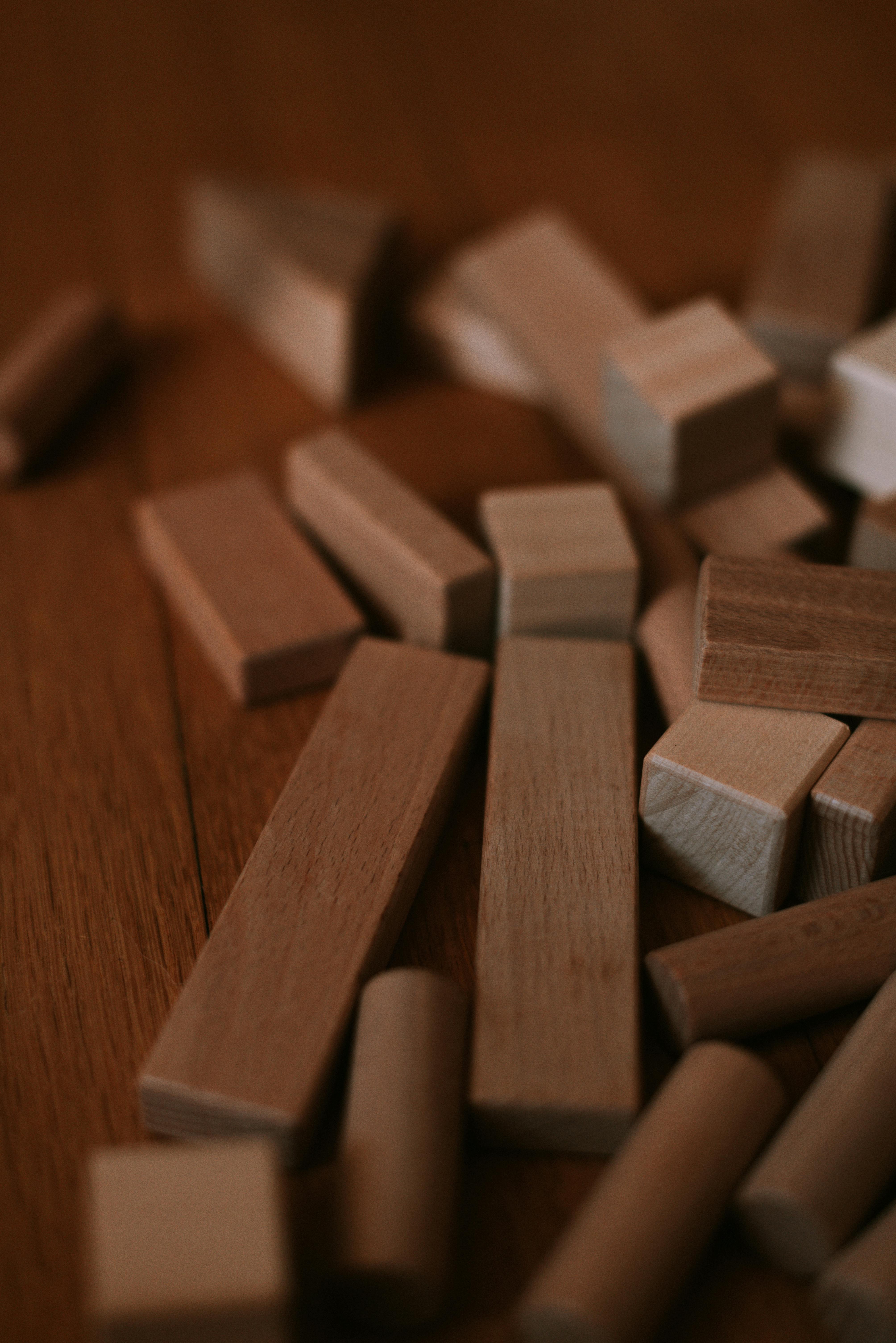 Scattered wooden building blocks on a wooden floor, emphasizing texture and craftsmanship.