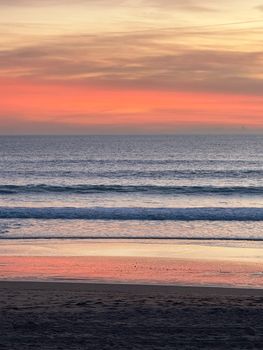 Peaceful sunset view with vibrant orange hues reflecting on the ocean waves.