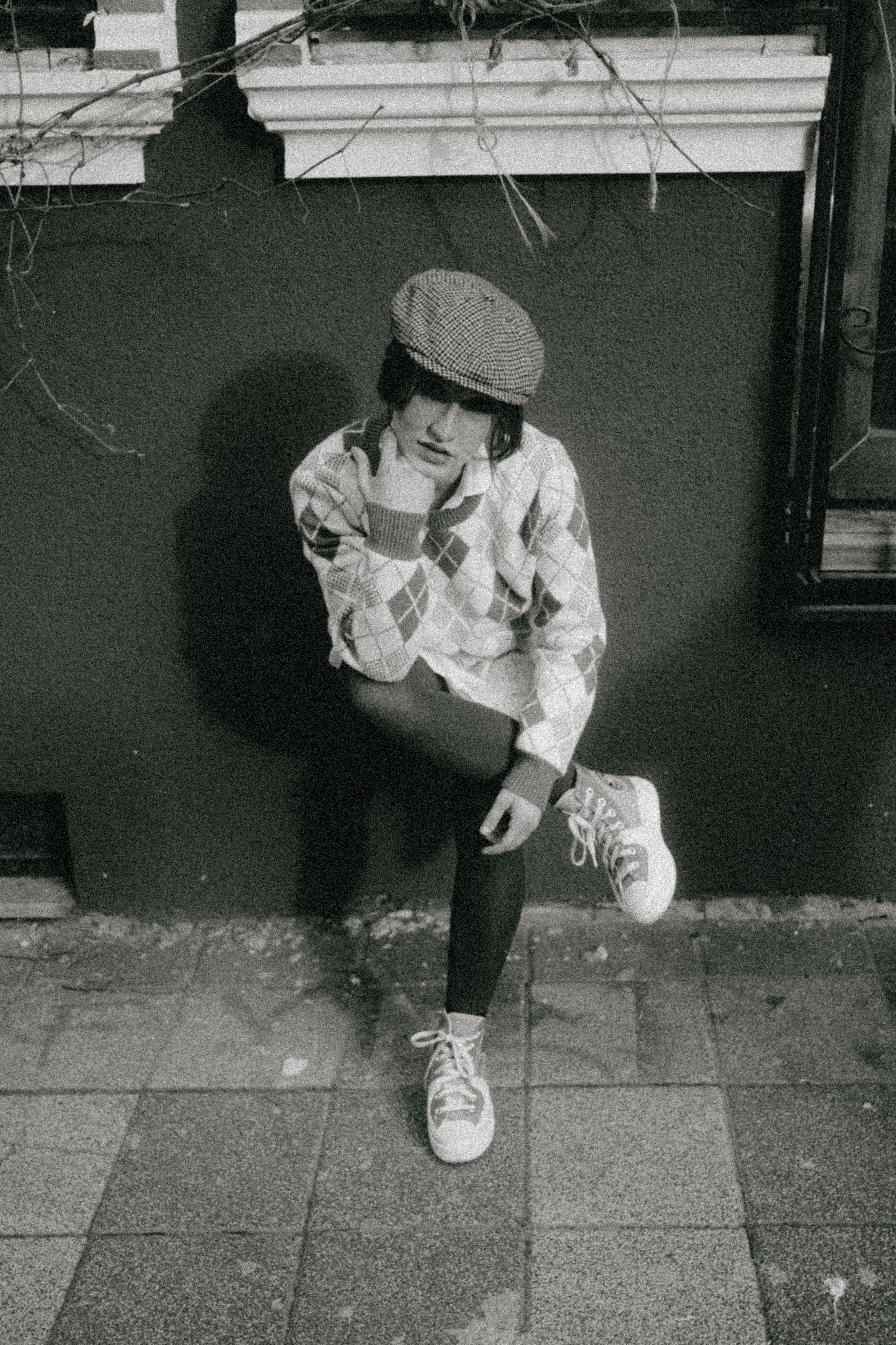 Teen dressed in vintage clothing poses thoughtfully in a city setting.