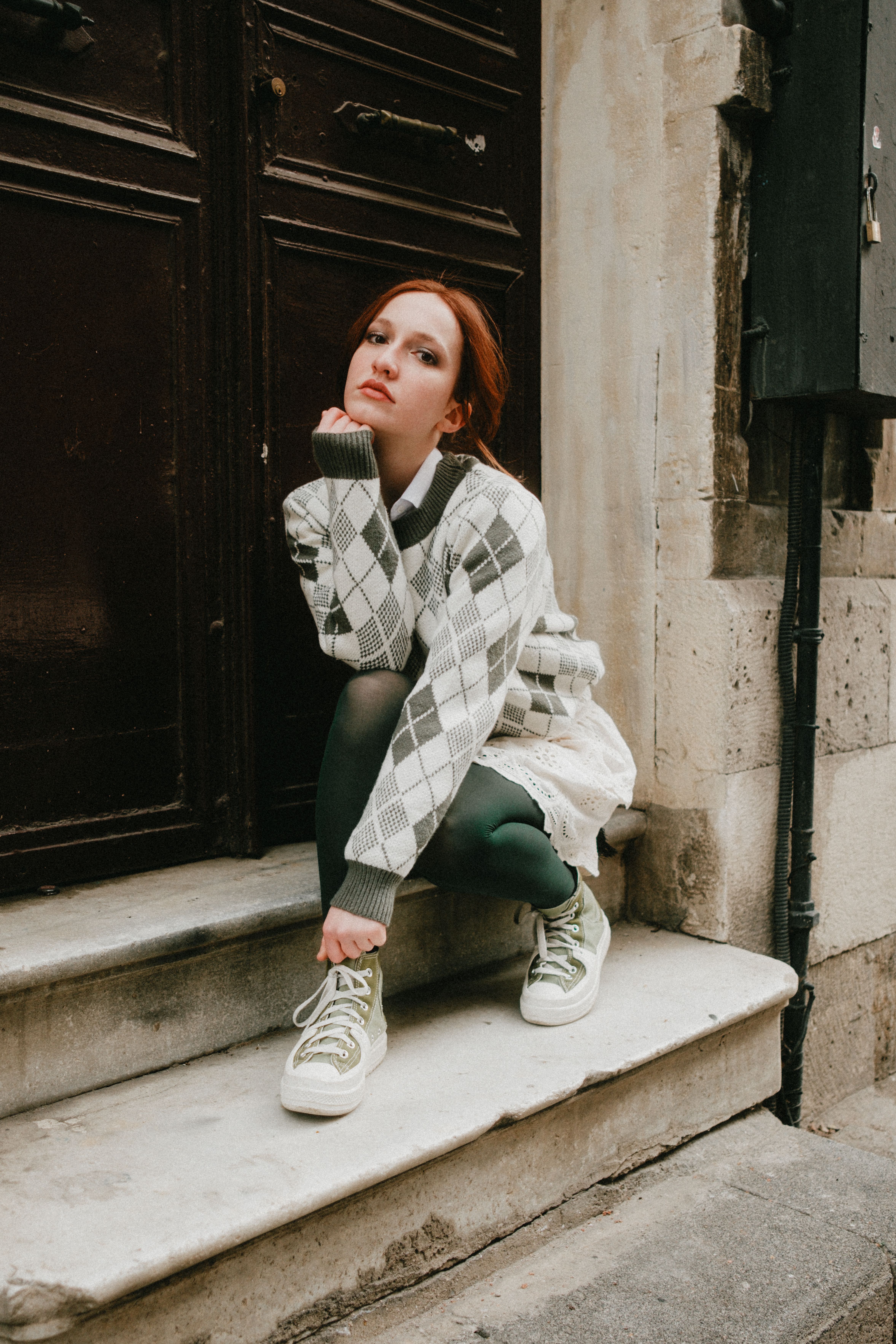 Fashionable young woman in urban setting wearing trendy sweater and sneakers.
