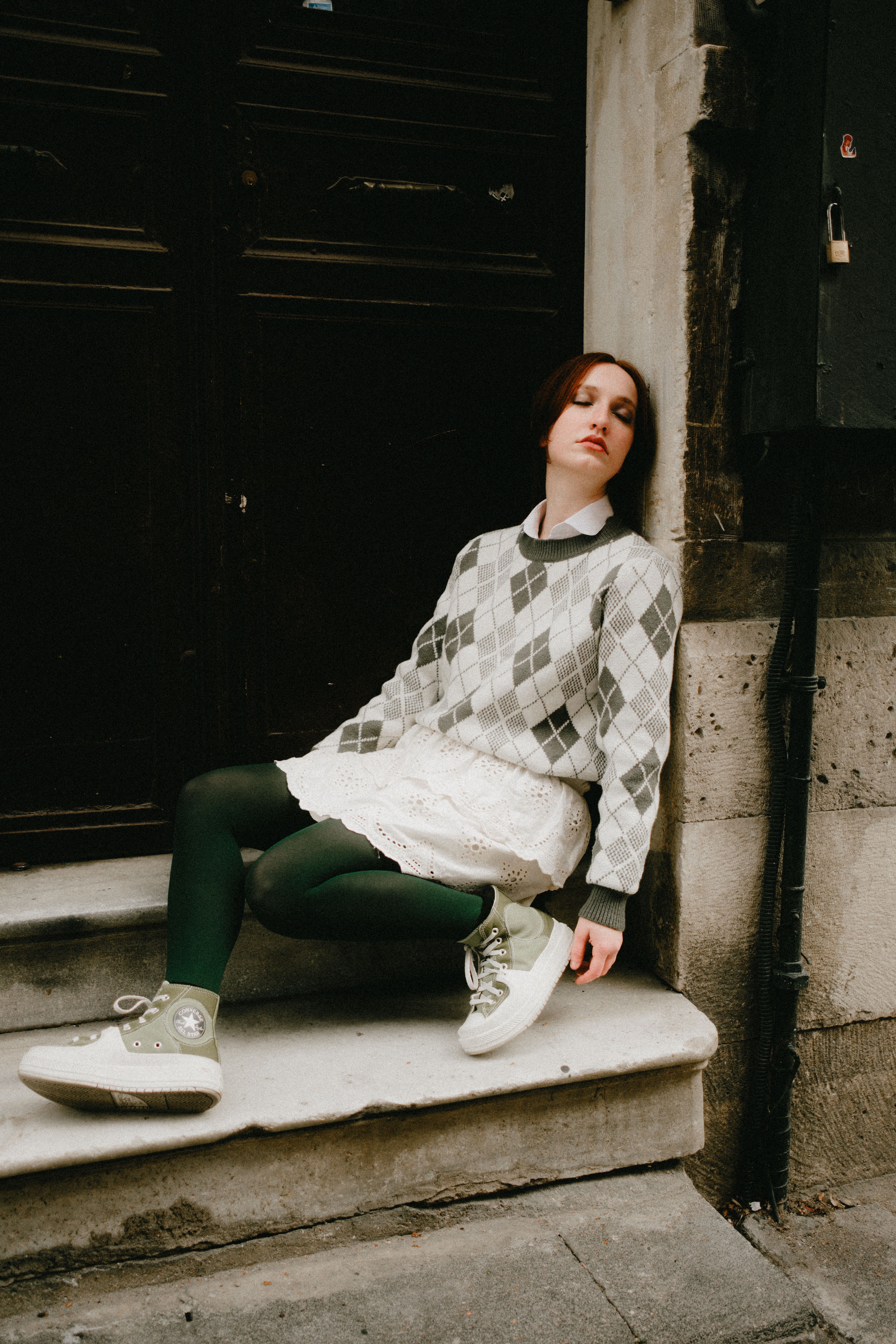 Young woman in fashionable attire posing on urban steps.