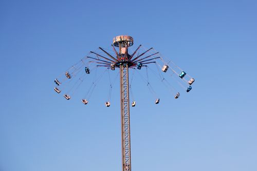 Free A vertical swing ride reaching high into a clear blue sky at an amusement park. Stock Photo