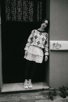 Stylish portrait of a woman in patterned sweater leaning against door.