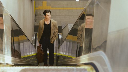 Free A young man in a modern outfit riding an escalator in a subway station. Stock Photo
