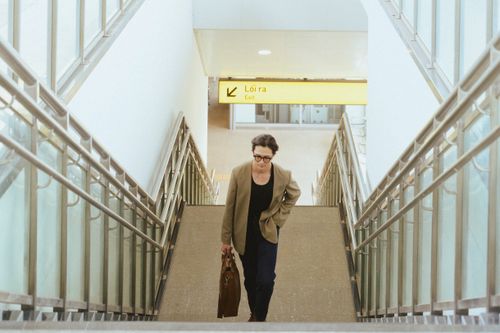 Free Businesswoman with briefcase climbing airport stairs towards exit sign marked 'Loira'. Stock Photo