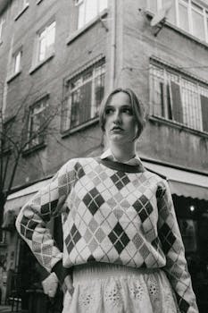 Black and white portrait of a woman in vintage attire, urban setting.