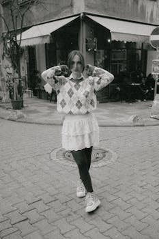 A stylish woman poses in street fashion with an argyle sweater and skirt.