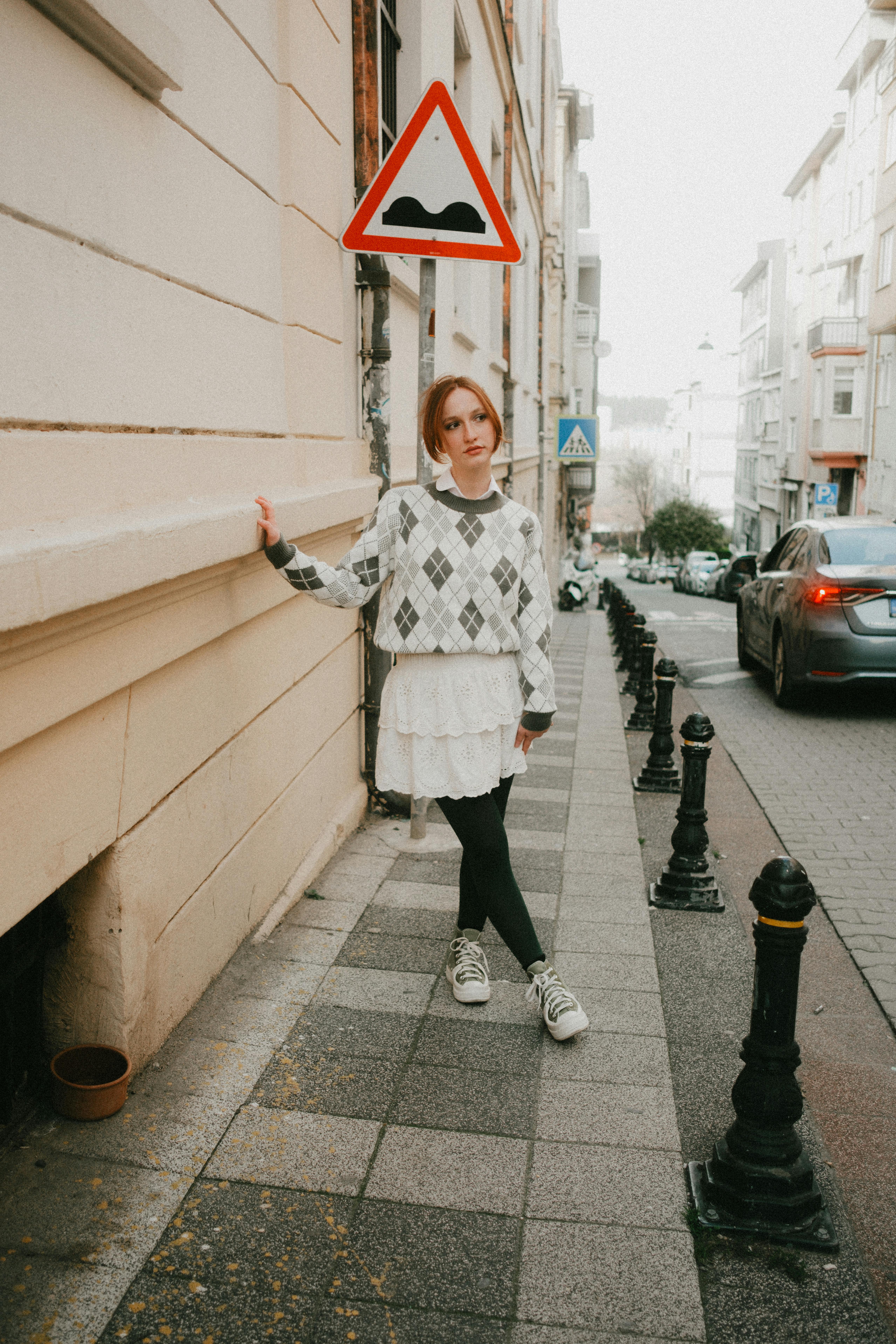 Stylish young woman poses on a street in Istanbul, featuring distinct city architecture.
