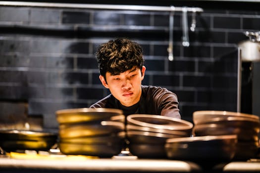Focused young chef working diligently to prepare dishes in a sleek modern kitchen setting.