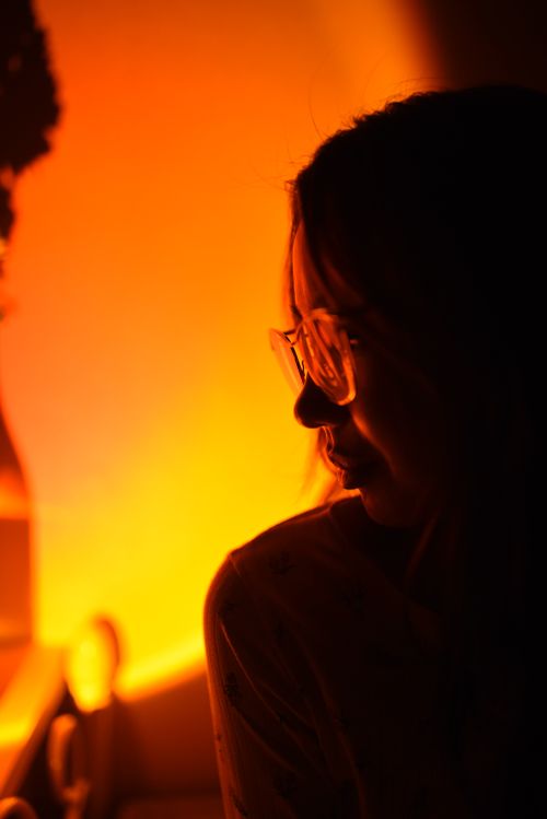 Free A woman's silhouette in warm, soothing candlelight creates a serene, introspective mood. Stock Photo
