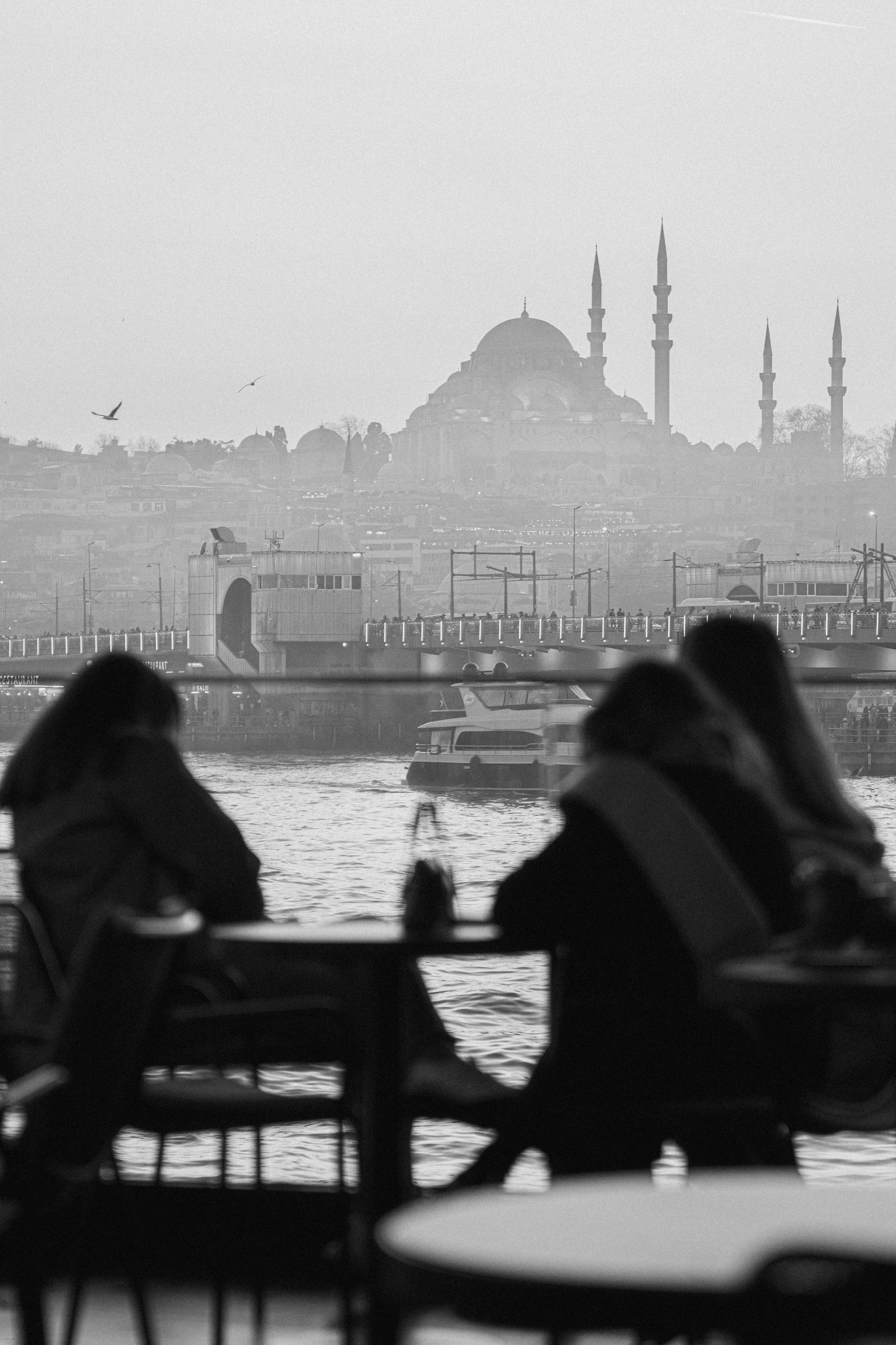 Silhouetted figures with Istanbul mosque skyline in black and white.