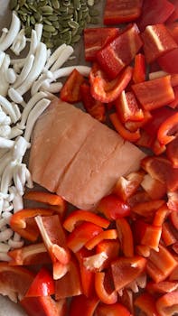 A vibrant display of salmon, red peppers, mushrooms, and pumpkin seeds for a healthy meal.