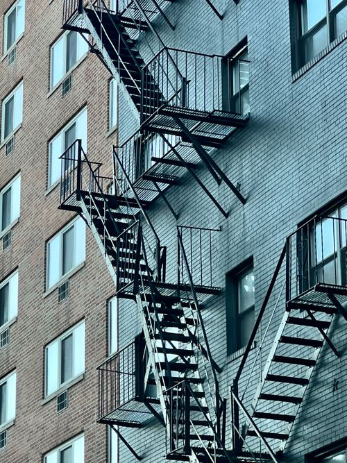 Free Vertical fire escapes on brick apartment buildings showcasing urban architecture. Stock Photo