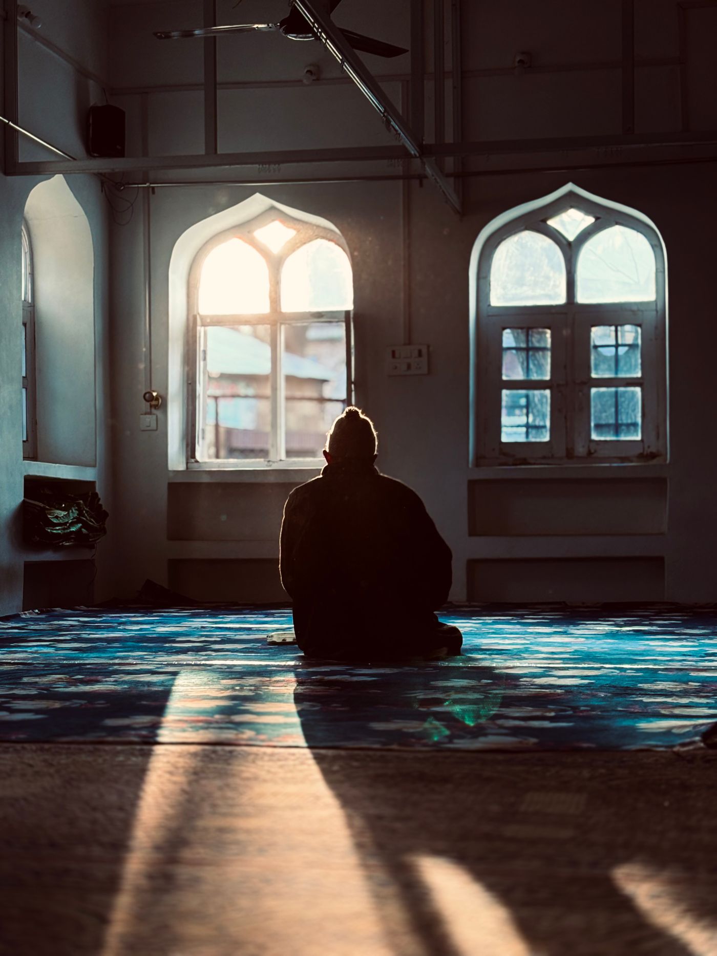 Sunlight through arched windows in a tranquil prayer space