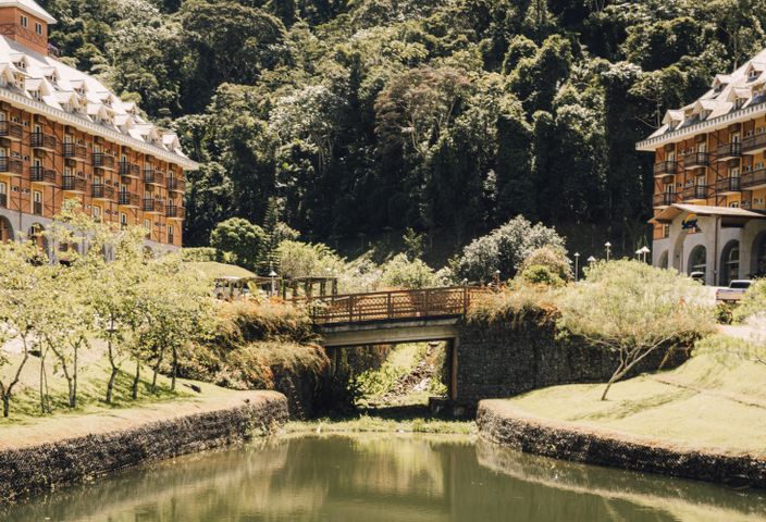 A beautiful resort with European architecture and a charming bridge amidst lush greenery.