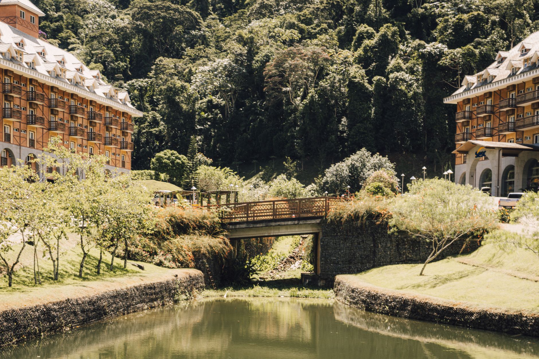 A beautiful resort with European architecture and a charming bridge amidst lush greenery.