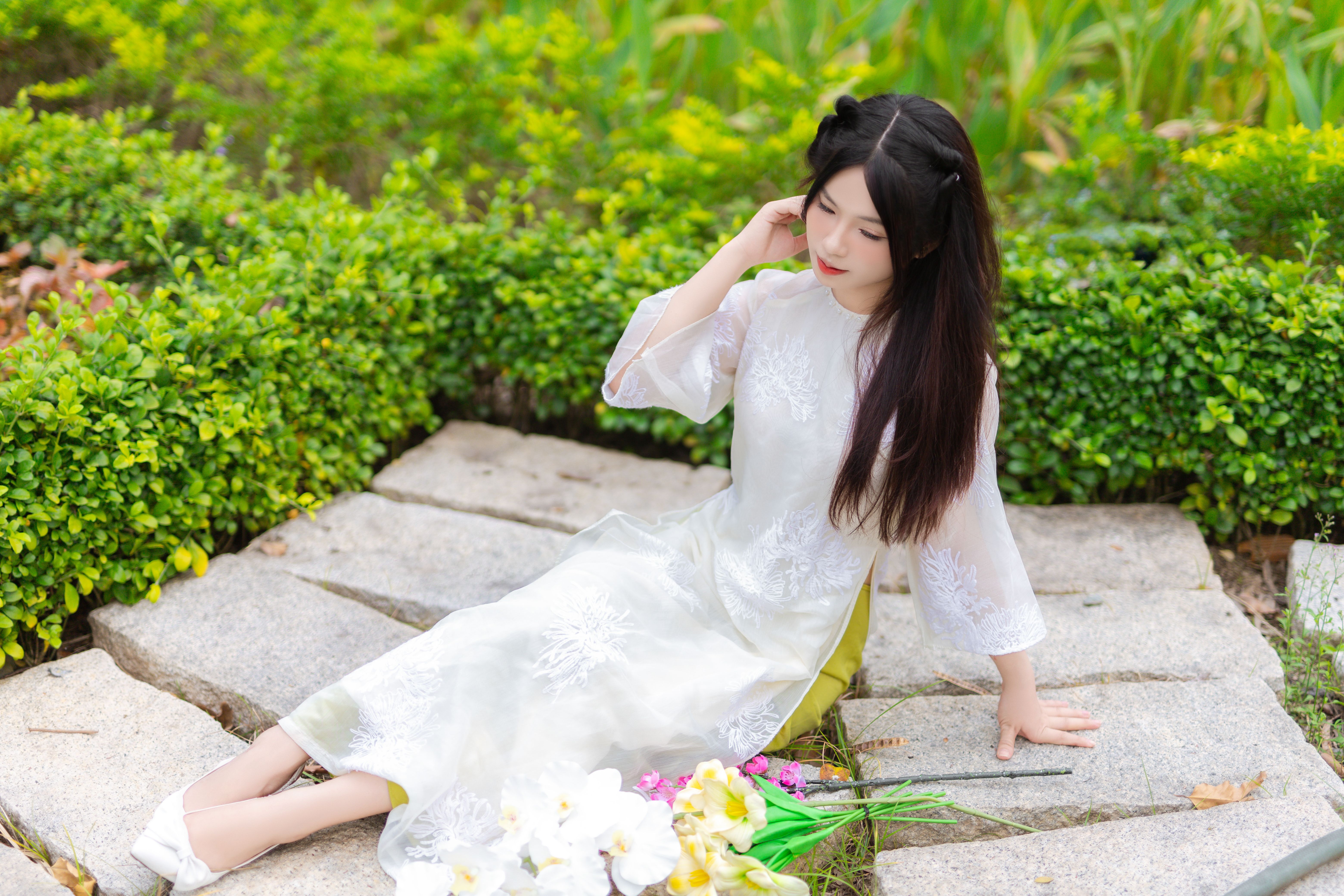 Young Woman in Traditional Dress Sitting on Garden Path · Free Stock Photo