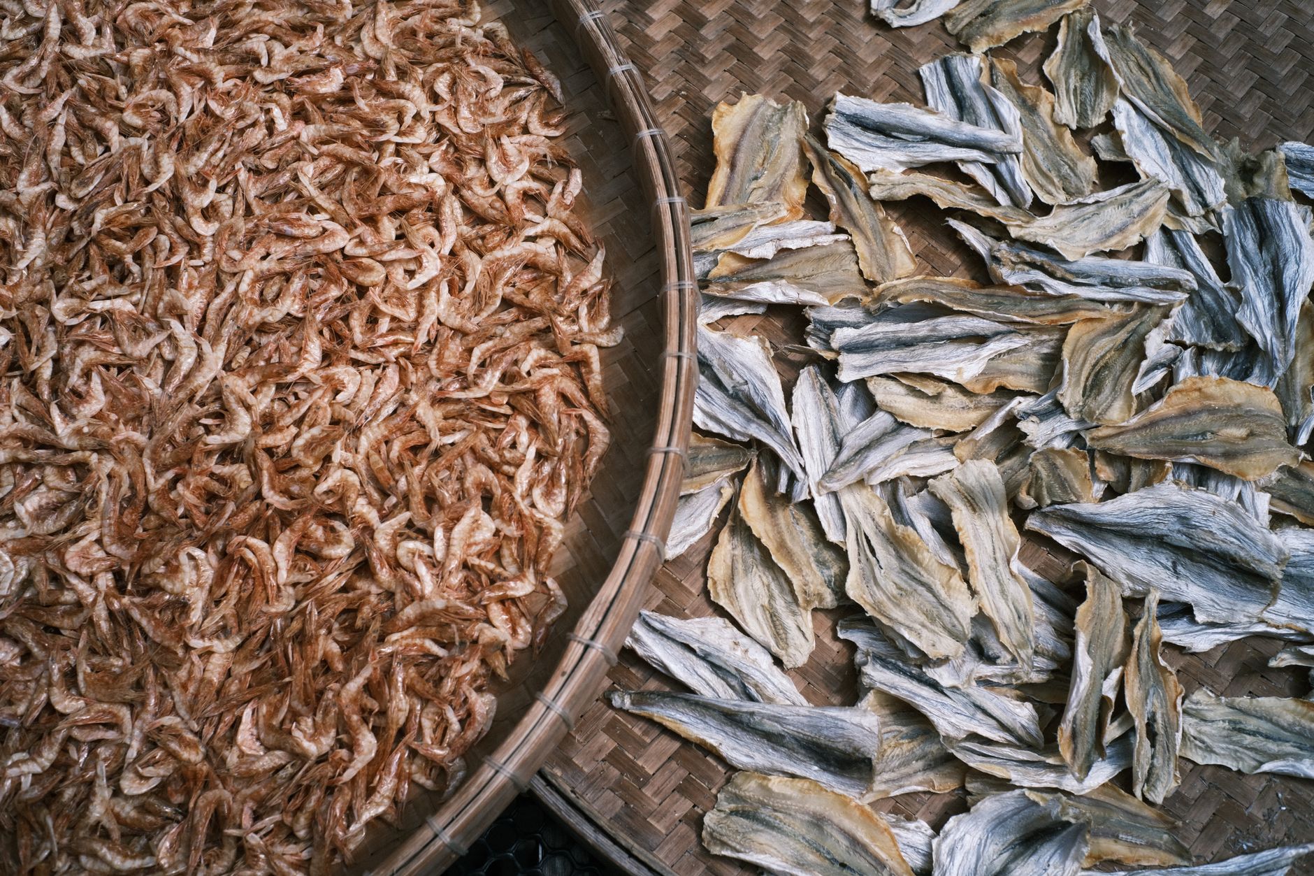 Top view of dried shrimp and fish on a bamboo tray, ideal for culinary themes.