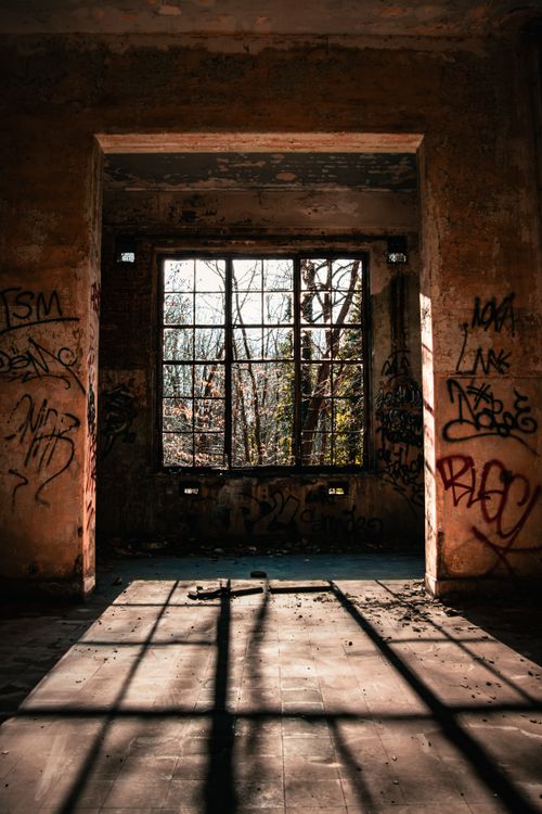 Free Explore the intriguing decay of an urban room adorned with graffiti and sunlight streaming through a broken window. Stock Photo