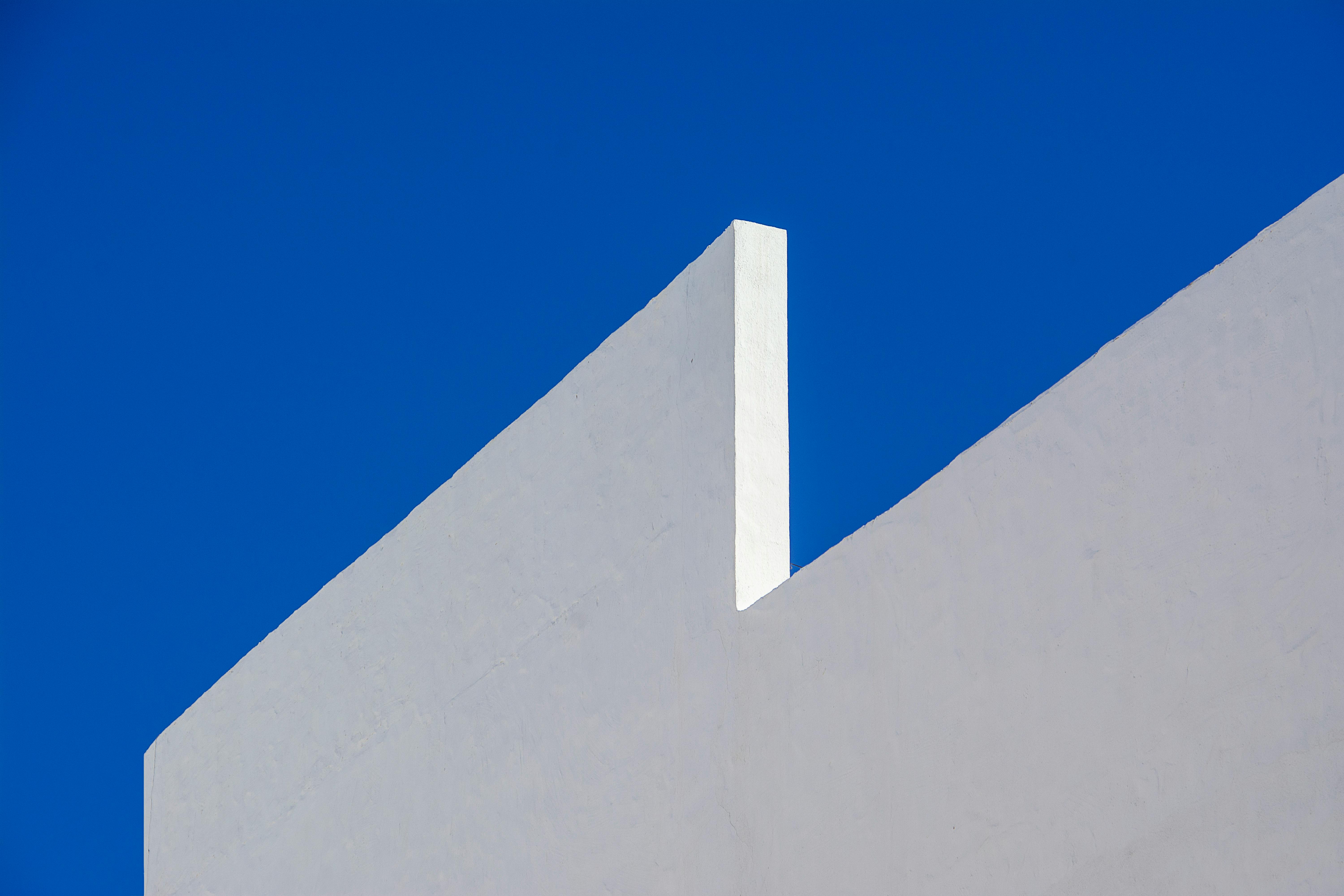 White geometric wall contrasts sharply against a vivid blue sky.