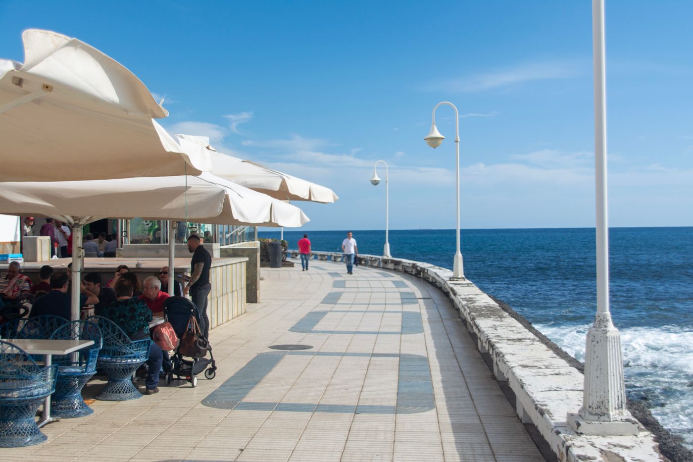 Paseo marítimo con sombrillas frente al mar en una mañana despejada de temporada