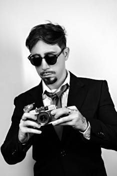 Black and white portrait of a stylish businessman taking a photo with a vintage camera.