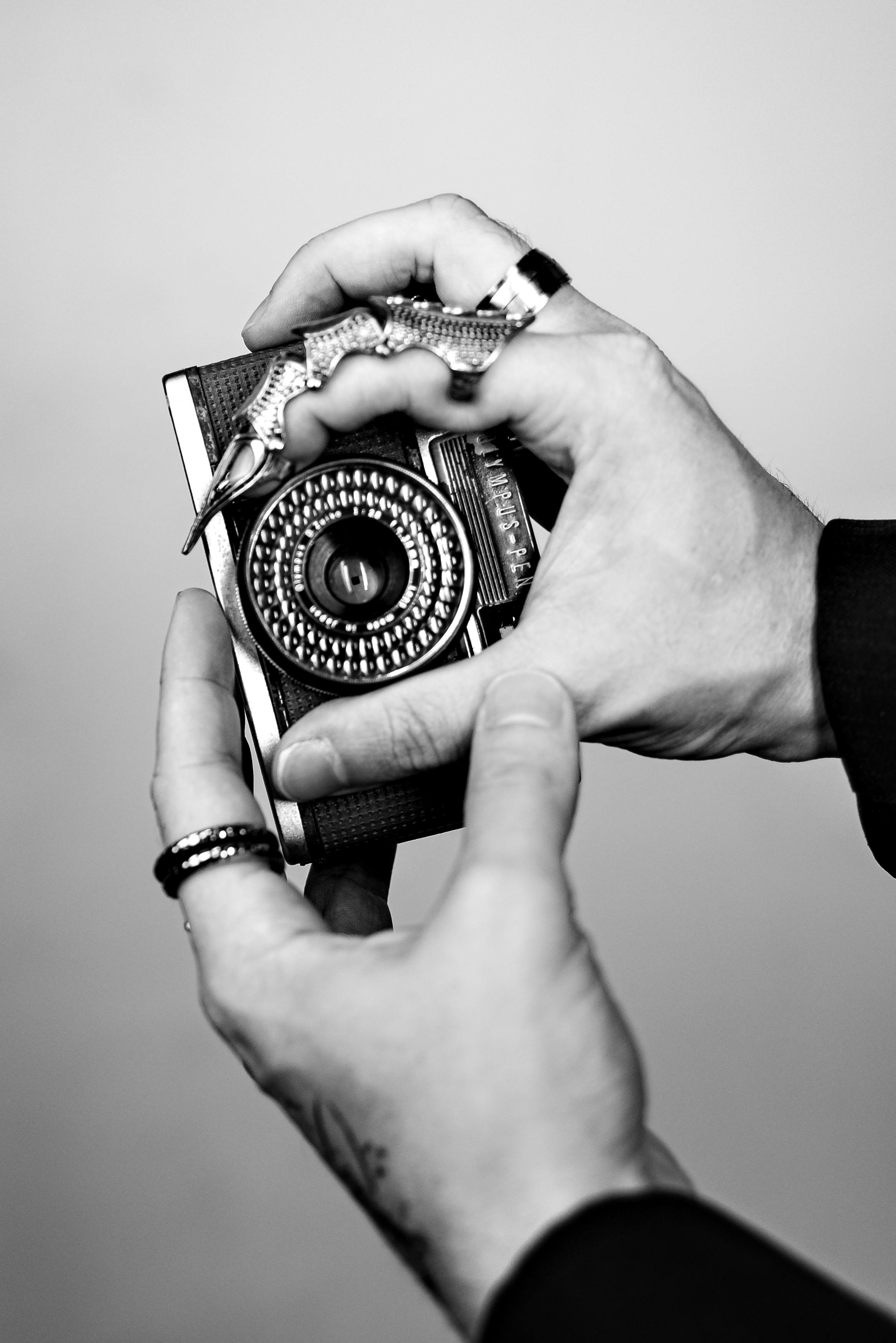 Gratis Una elegante imagen en blanco y negro de manos sosteniendo una cámara vintage, adornada con anillos. Foto de stock