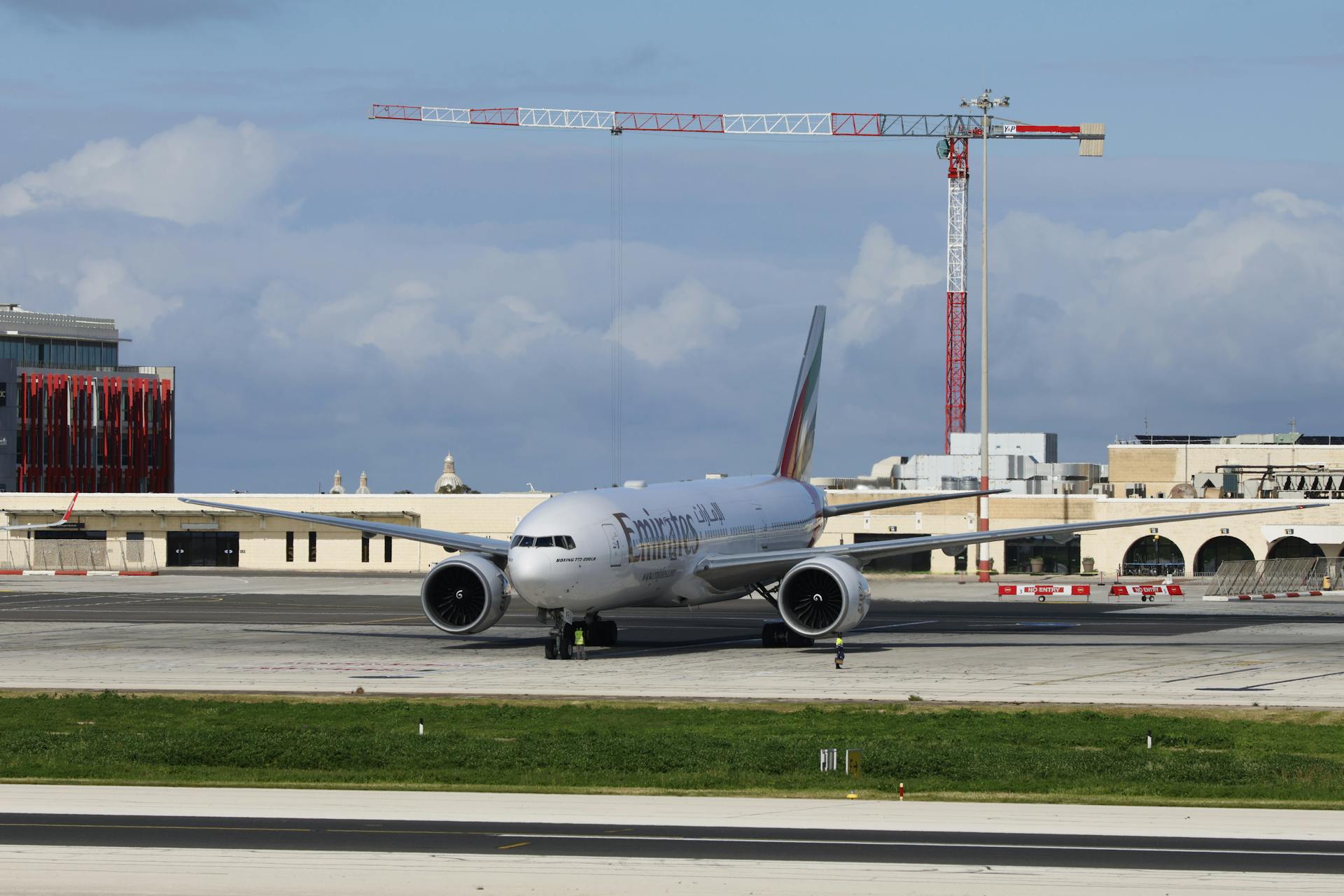 Aircraft on tarmac at airport with clear blue sky and construction crane.