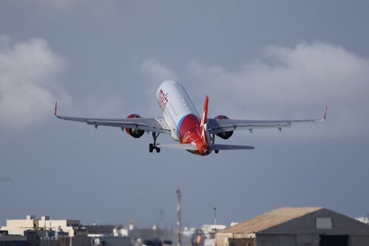Airplane ascending over city buildings against a clear sky, creating a dynamic travel scene.