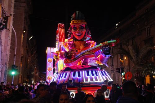 Free Colorful neon-lit parade float featuring a giant musician and keyboard at night. Stock Photo