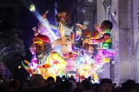 Colorful illuminated float at a nighttime festival with large whimsical figures.