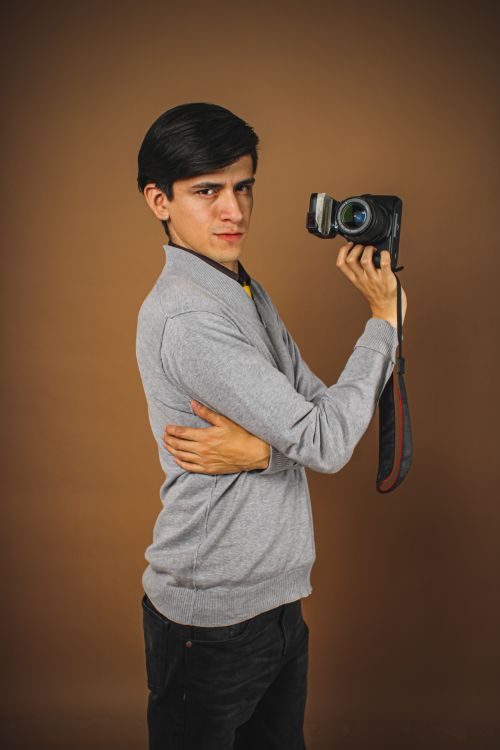 Free Studio portrait of a young male photographer with a classic camera in casual attire. Stock Photo